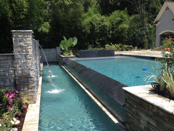 A modern vanishing edge pool with sheer descents flowing into the pool.