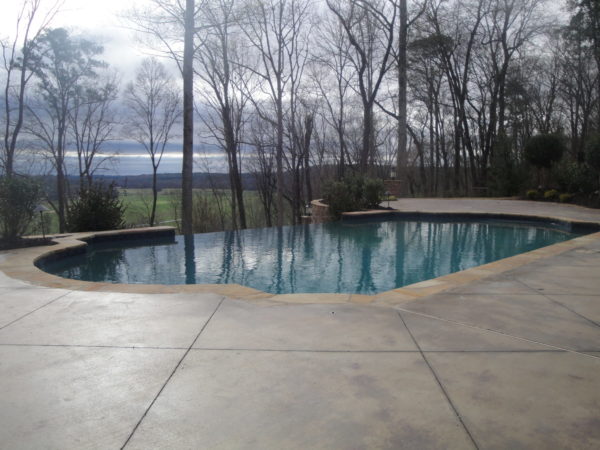 A modern vanishing edge pool with a view of the lush green fairways of a golf course.