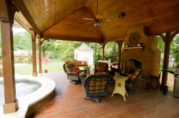 A picturesque detailed wood vaulted cabana with a cozy fireplace, nestled by the poolside.