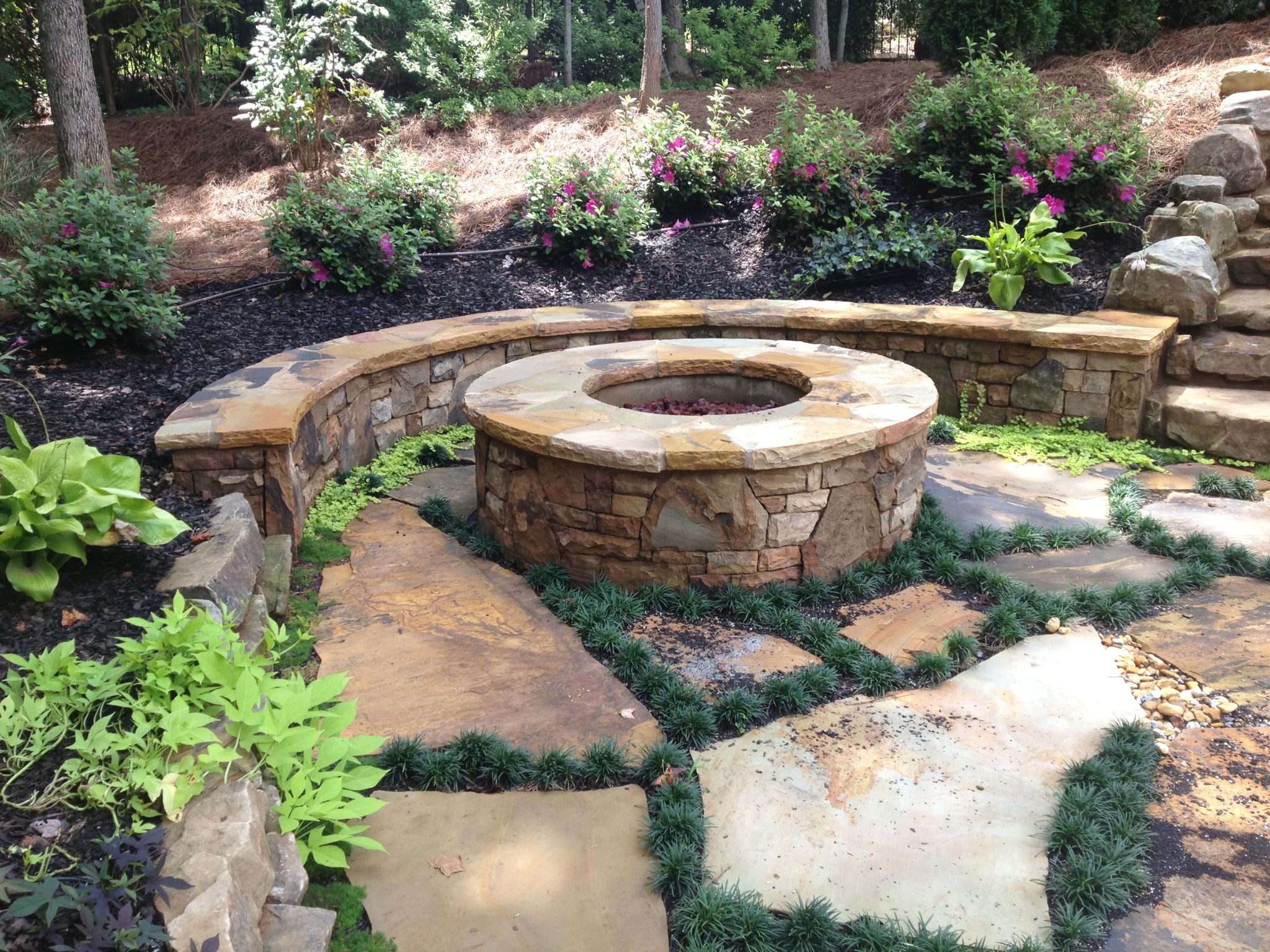 A cozy fire pit surrounded by a stone bench, offering a serene retreat by the poolside.
