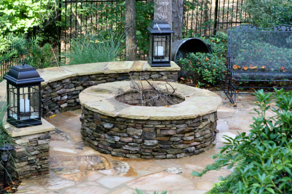 A cozy fire pit surrounded by a stone bench, offering a serene retreat by the poolside.