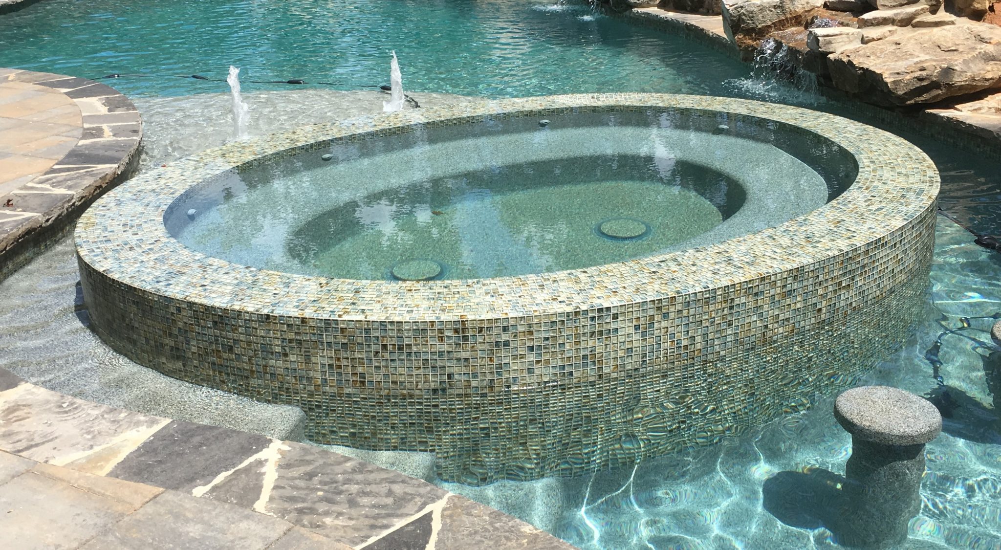 A raised circular spa with custom tilework and integrated barstools for added convenience.