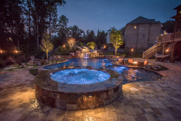 Aerial view of a custom freeform pool with a waterfall and sunken fireplace surrounded by lush landscaping.