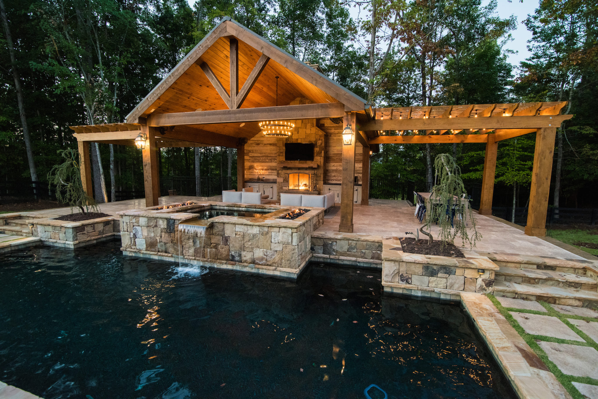 A luxurious poolside cabana with pergolas on each side, showcasing an outdoor kitchen.