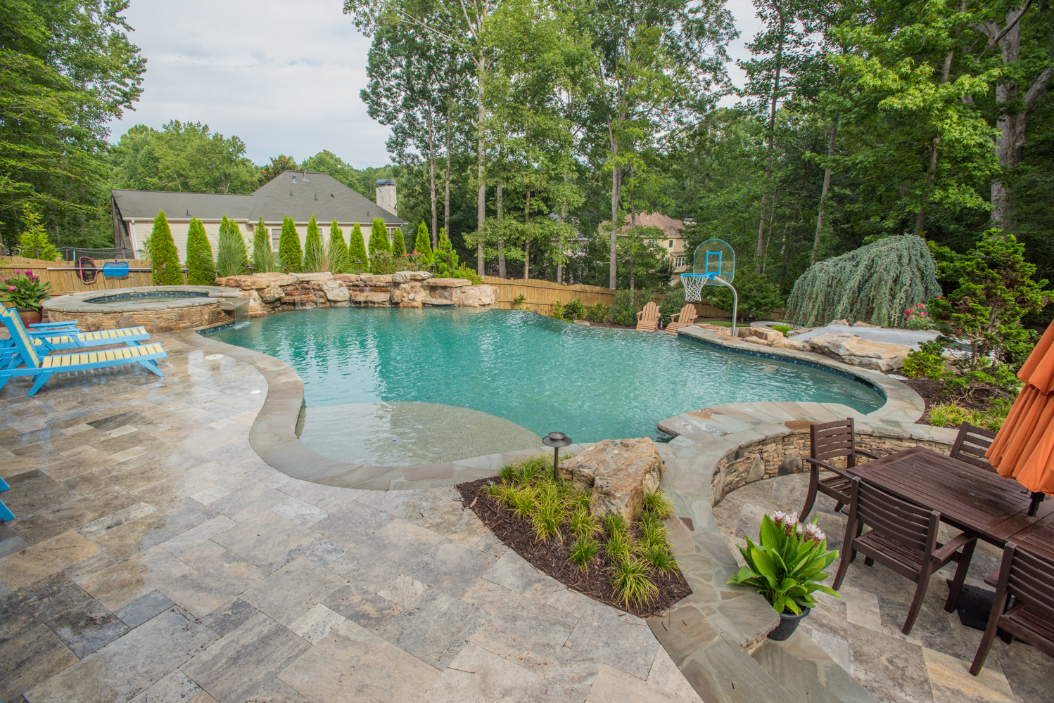 A custom freeform pool with a boulder waterfall surrounded by lush greenery.