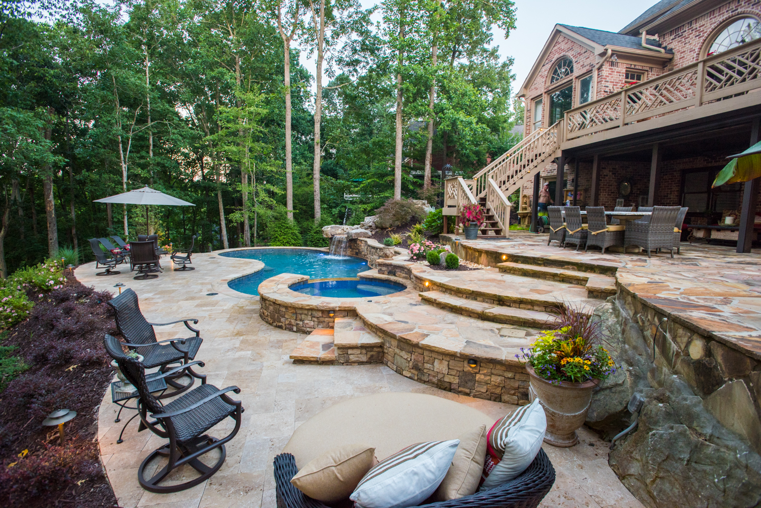 A custom freeform pool with a stunning boulder waterfall surrounded by lush landscaping.
