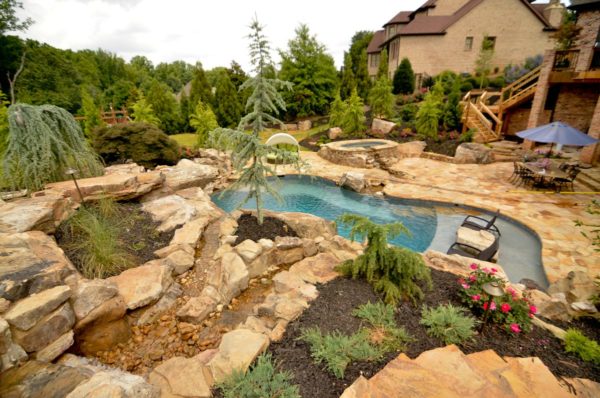 A custom freeform pool surrounded by landscaping, featuring a mesmerizing boulder waterfall.
