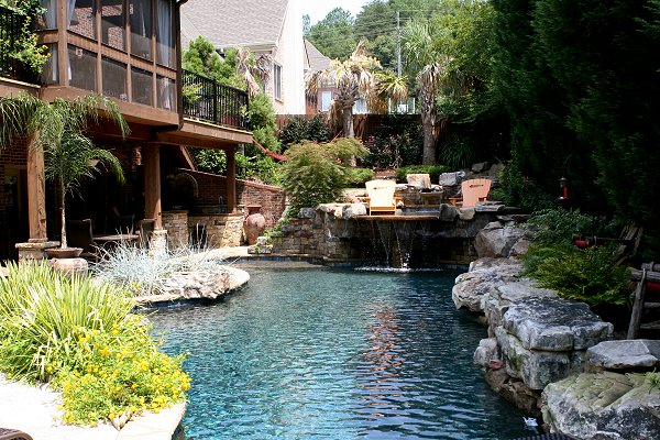 A custom freeform pool with a boulder waterfall and grotto nestled in lush landscaping.