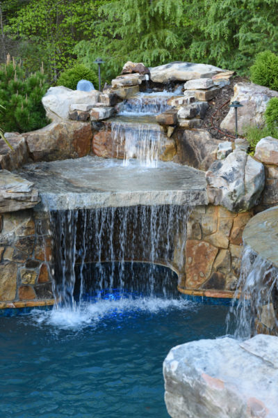 A breathtaking view of Cascade Haven, a pool adorned with a custom three-tier boulder waterfall and grotto.