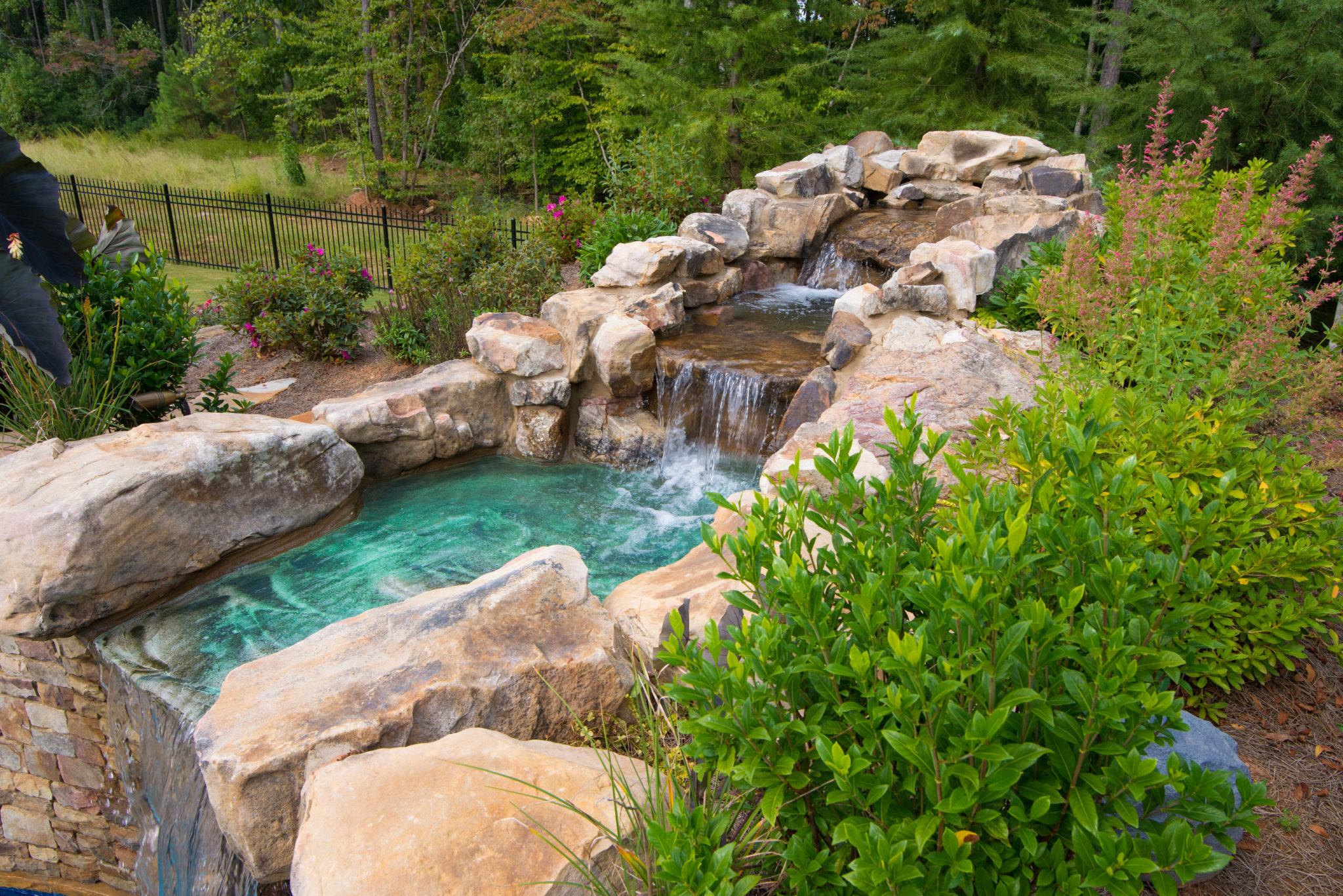 A custom two-tier cascading waterfall flowing into a small pool before cascading into a larger pool.