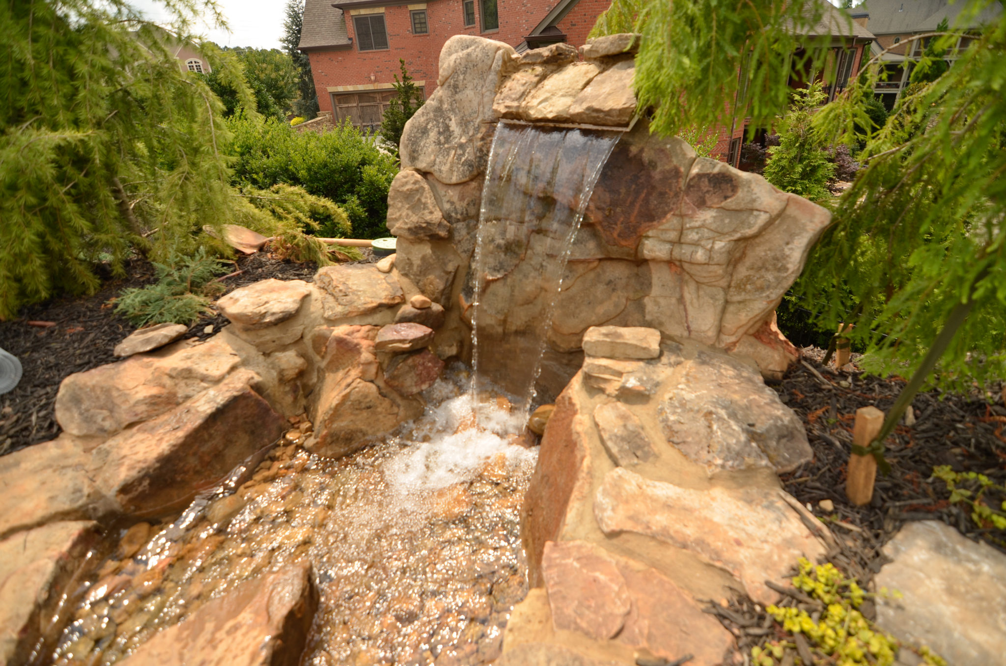 A custom sheer descent waterfall gracefully flowing into a tranquil pond.