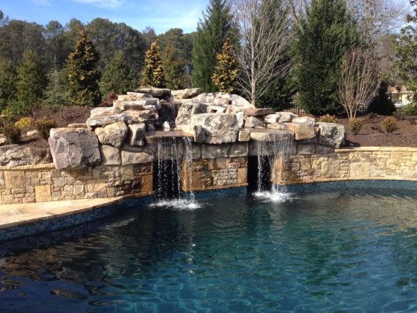 A custom boulder waterfall grotto with two entrances in a swimming pool.