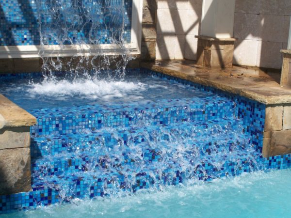 A three-tier tile waterfall cascading into a swimming pool.