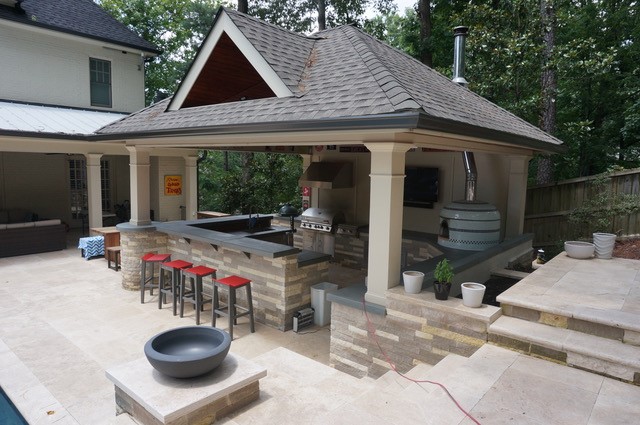 A picturesque wood vaulted cabana with a fully equipped kitchen and pizza oven, overlooking a luxurious swimming pool.