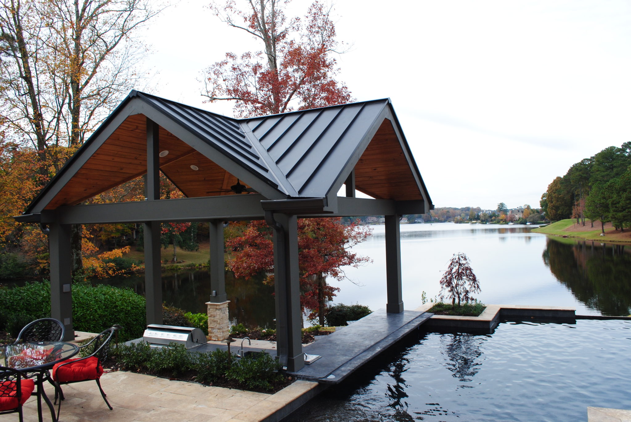 A serene lakeside scene featuring a detailed wood vaulted cabana overlooking the water.