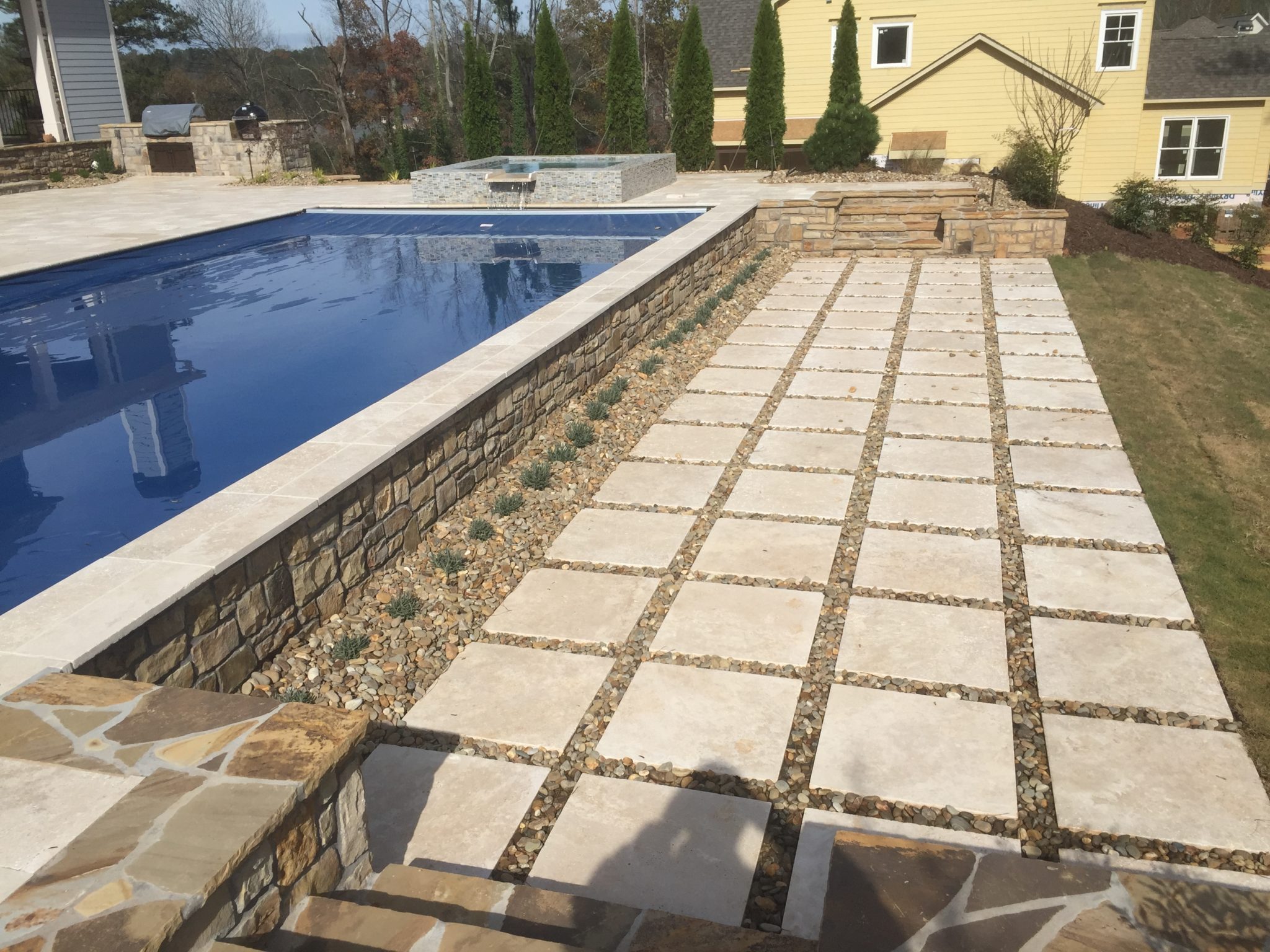Custom straight line pool with travertine tiles measuring 2' x 2'.