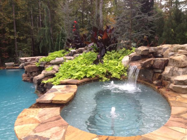 A kidney-shaped spa with a cascading waterfall, offering a serene and picturesque addition to your outdoor sanctuary.