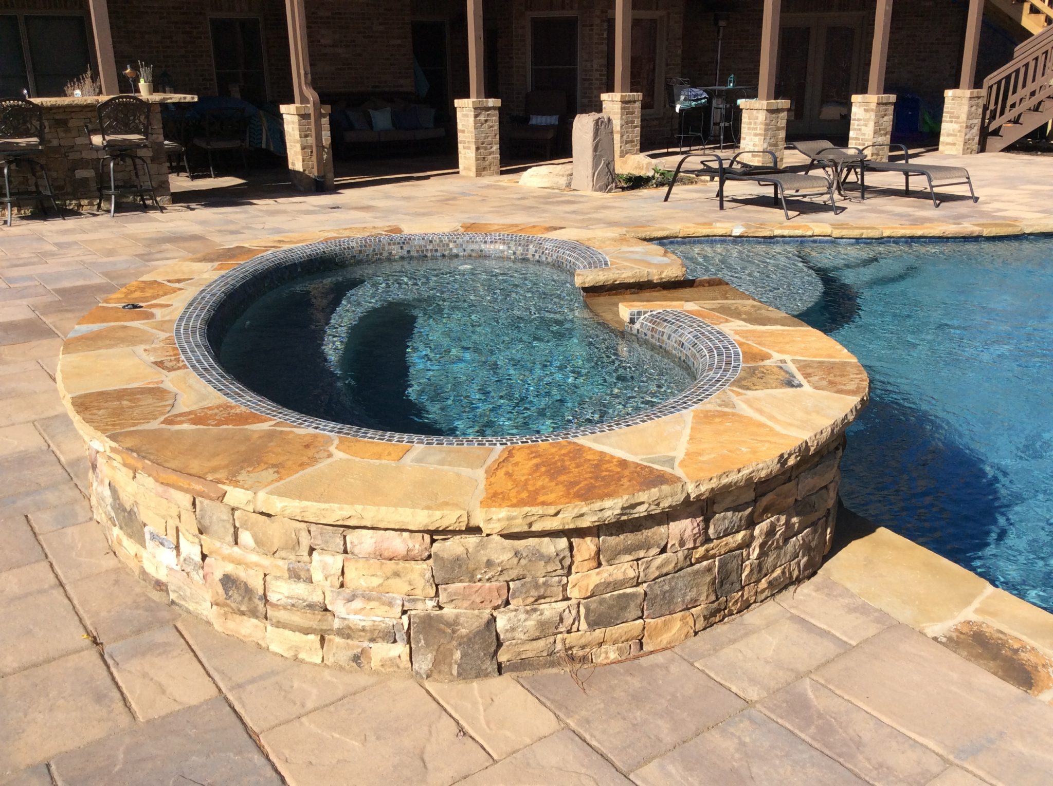 A kidney-shaped spa with a gentle spillover, offering a serene and luxurious addition to your outdoor sanctuary.