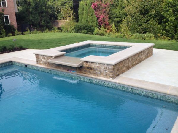 A sleek square spa with a gentle spillover, epitomizing modern elegance and relaxation in your outdoor oasis.