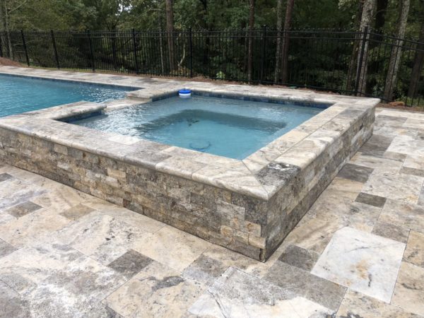 A sleek square spa with a gentle spillover, epitomizing modern elegance and relaxation in your outdoor oasis.