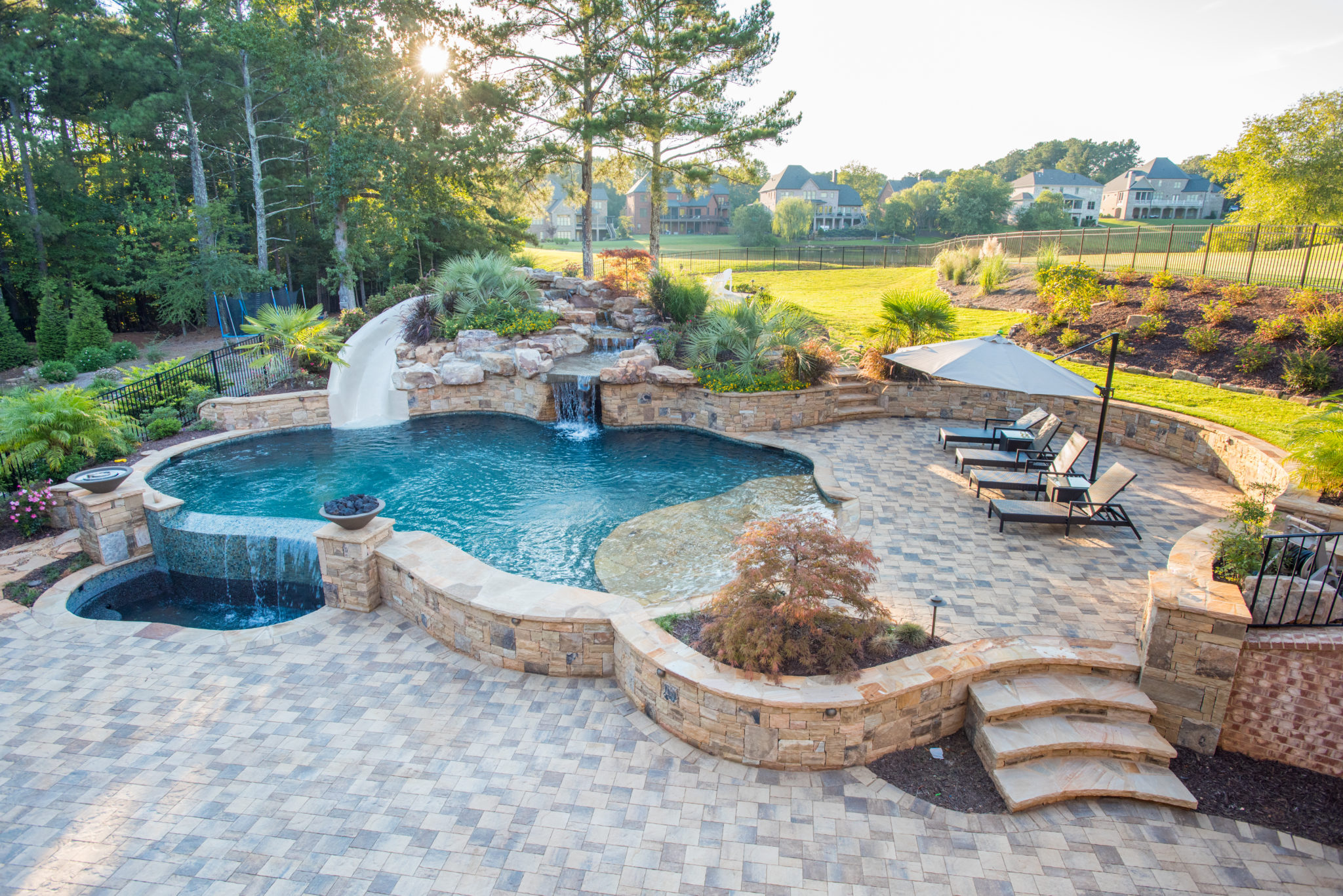 Aerial view of a custom raised freeform pool with a vanishing edge boulder waterfall and slide.