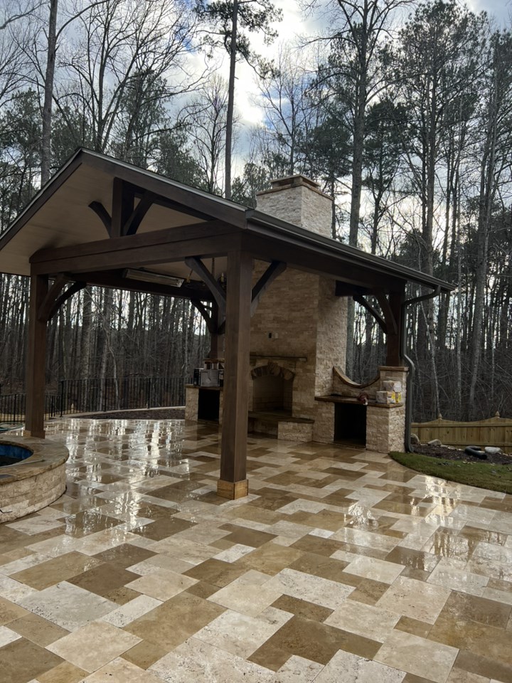 A stylish cabana with a charming stone fireplace, offering a cozy outdoor retreat.