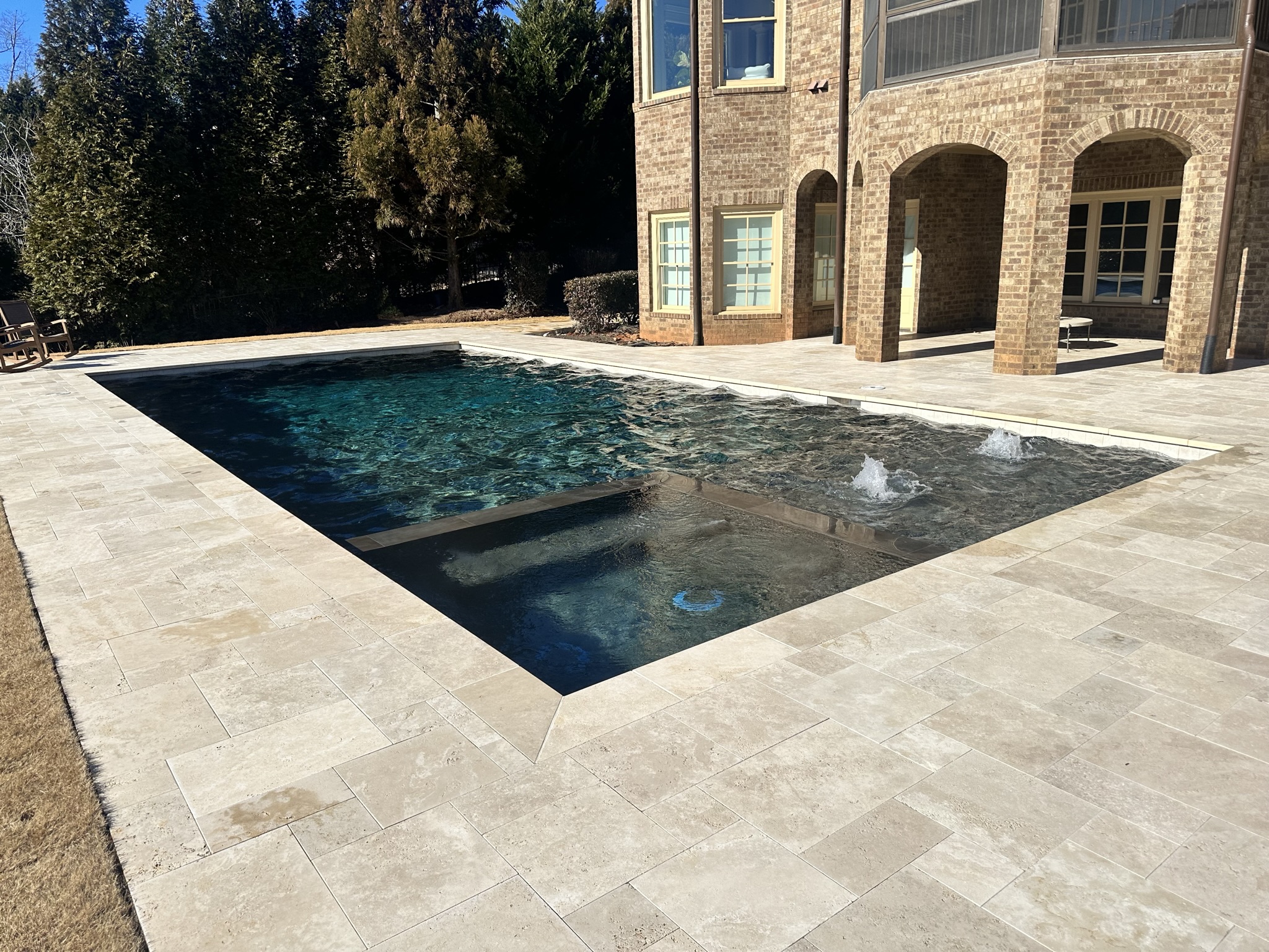 A modern straight-line pool with an adjacent spa, located at The Manor golf course.