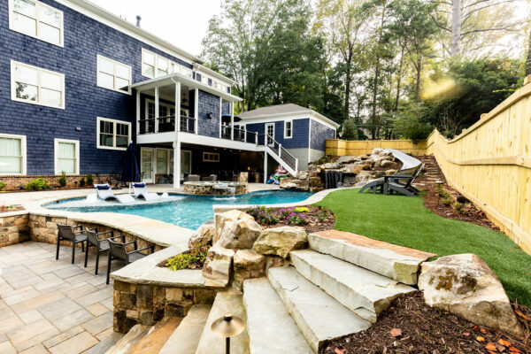 A stunning pool surrounded by a two-tier deck, featuring a cozy fireplace for a warm and inviting outdoor escape.