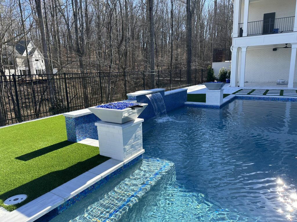 Elegant modern swimming pool with clean lines and a 360-degree spa, designed with glass tile accents at Hawks Ridge