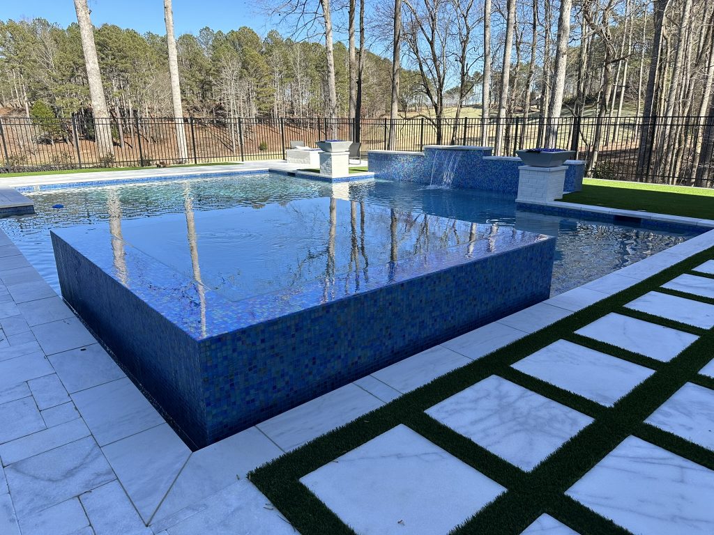 Elegant modern swimming pool with clean lines and a 360-degree spa, designed with glass tile accents at Hawks Ridge