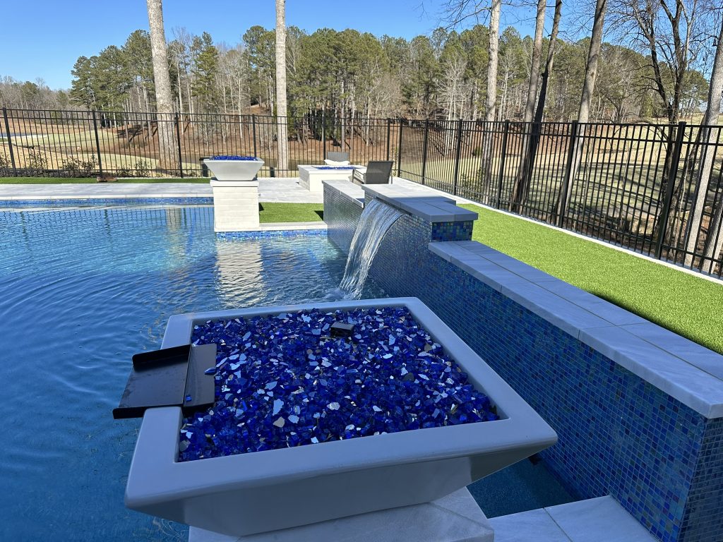 Elegant modern swimming pool with clean lines and a 360-degree spa, designed with glass tile accents at Hawks Ridge