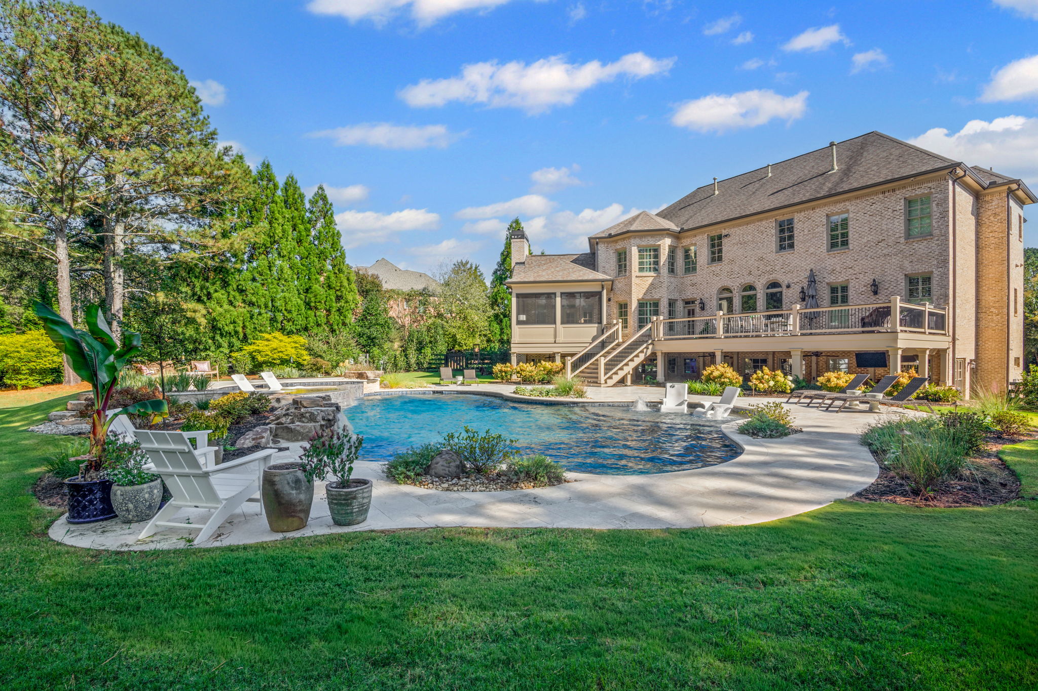 Elegant modern swimming pool with an upper tanning ledge, custom waterfall feature, and beautifully designed landscape.