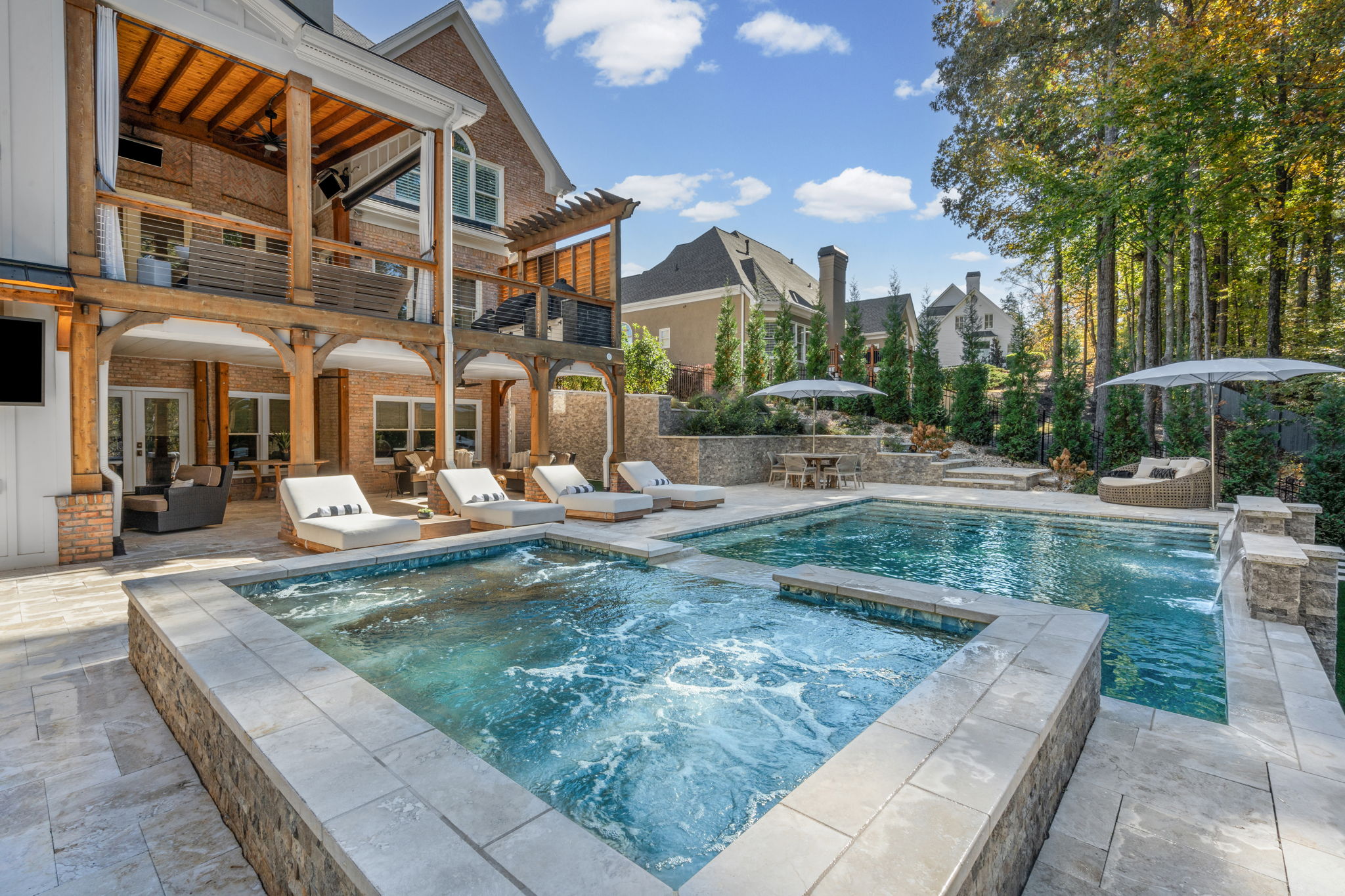 Modern straight-line swimming pool with integrated spa, luxury hardscaping, and extensive outdoor living features