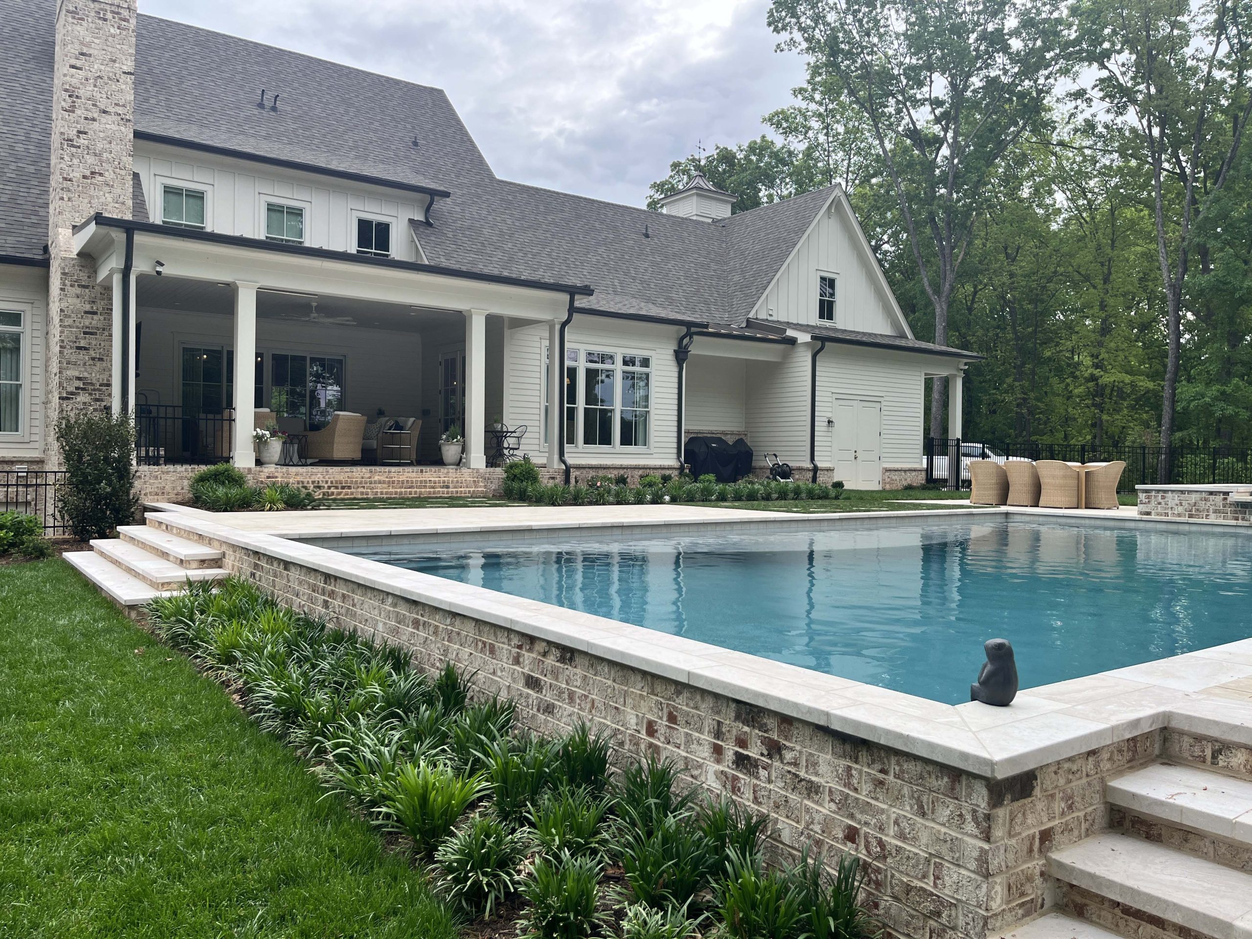 Modern elegant swimming pool surrounded by lush green landscaping and premium artificial turf.