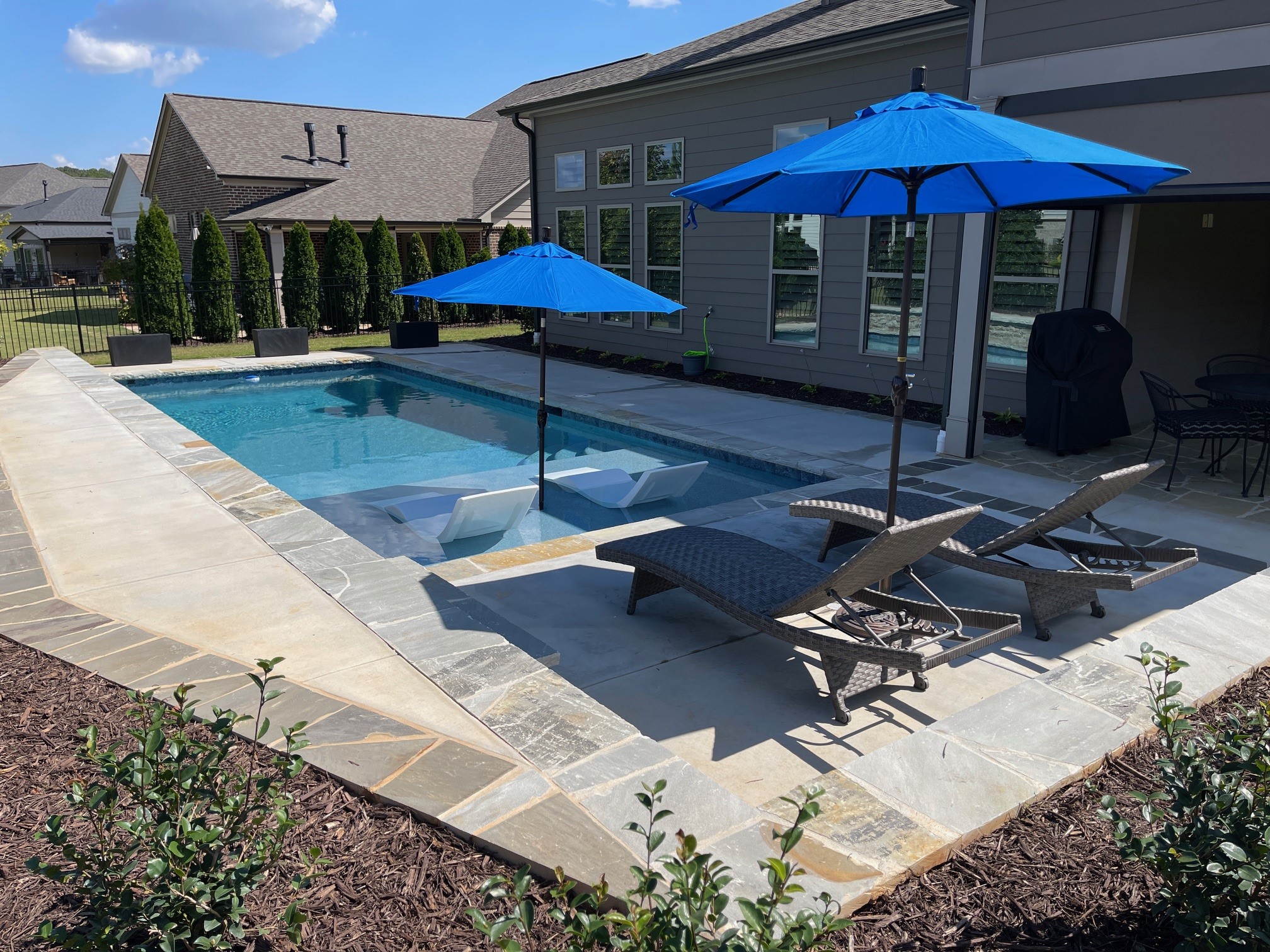 Classic rectangular pool with tanning ledge, in-pool loungers, and stone coping