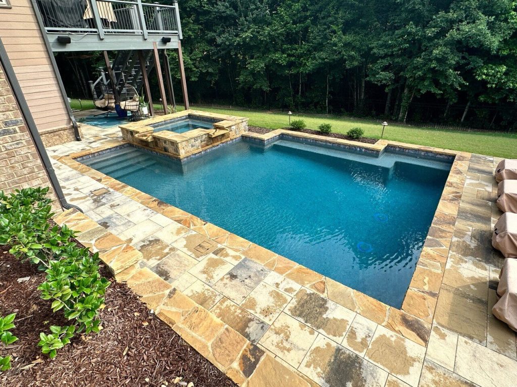 Rectangular shotcrete pool with raised stone spa, entry steps, and flagstone decking